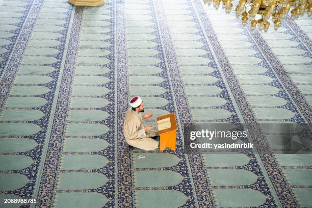 young male imam reading the quran in the mosque during ramadan. - kazakhstan stock pictures, royalty-free photos & images