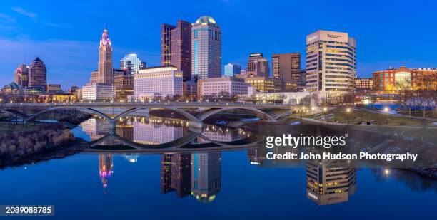 columbus ohio downtown skyline as seen from the banks of the scioto river on a late winter evening - river scioto stock pictures, royalty-free photos & images