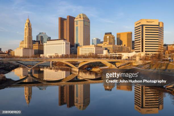 columbus ohio downtown skyline as seen from the banks of the scioto river on a late winter evening - river scioto stock pictures, royalty-free photos & images