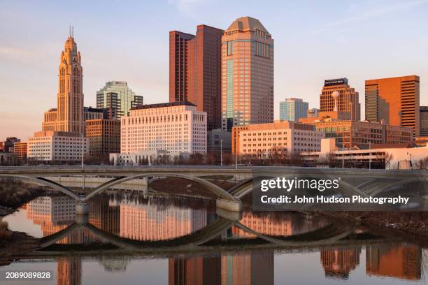 columbus ohio downtown skyline as seen from the banks of the scioto river on a late winter evening - river scioto stock pictures, royalty-free photos & images