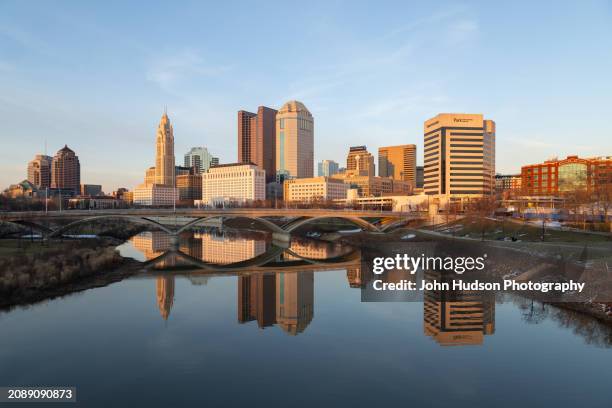 columbus ohio downtown skyline as seen from the banks of the scioto river on a late winter evening - river scioto stock pictures, royalty-free photos & images