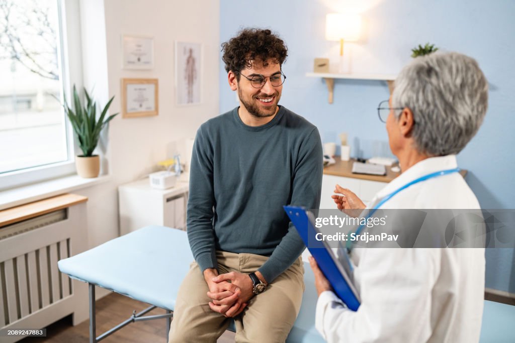 Paciente do sexo masculino fazendo check-up médico anual com uma médica caucasiana sênior, na ordenação
