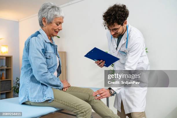 orthopedist examining senior female patient's knee - ortopedista imagens e fotografias de stock