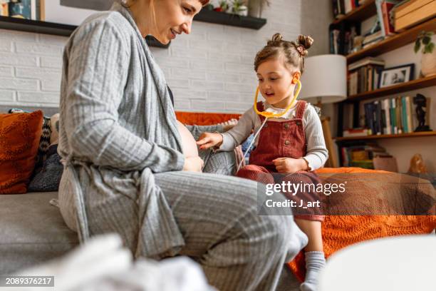 happy daughter listening to a baby in the big belly of her pregnant mom. - cute belly stock pictures, royalty-free photos & images