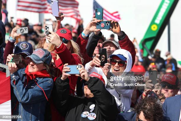 Guests take pictures as Republican presidential candidate former President Donald Trump's plane lands for a rally at the Dayton International Airport...