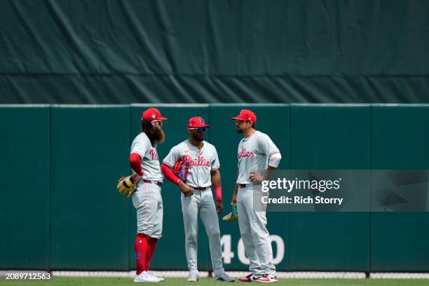 Brandon Marsh, Johan Rojas and Nick Castellanos of the Philadelphia Phillies look on during a spring training game against the Miami Marlins at Roger...