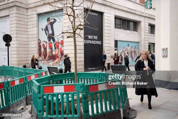 Pedestrians walk through an urban landscape of roadworks and retail businesses on the corner of Sackville and Vigo streets in Mayfair, on 18th March...