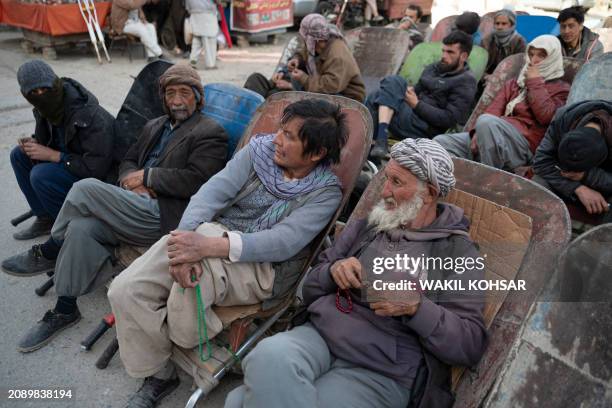 Afghan daily workers sit on their wheelbarrows while waiting for work along a roadside in Kabul on March 19, 2024.