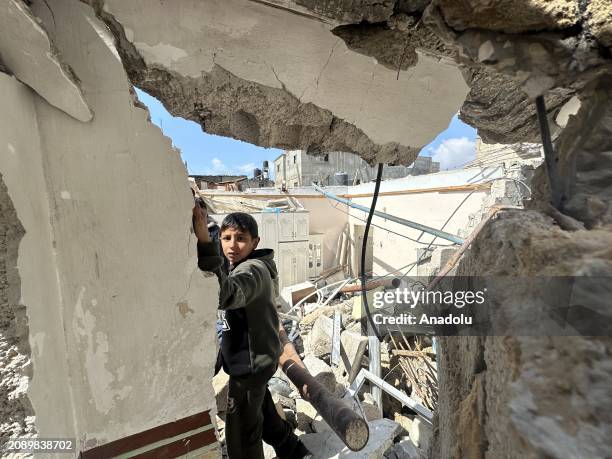 Palestinians, including children, collect remaining belongings from the rubble of destroyed houses and examine the rubble of collapsed buildings...