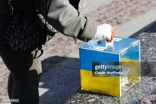 Person puts a banknote into a money box during the demonstration of Ukrainians in Krakow, Poland on March 19, 2024.