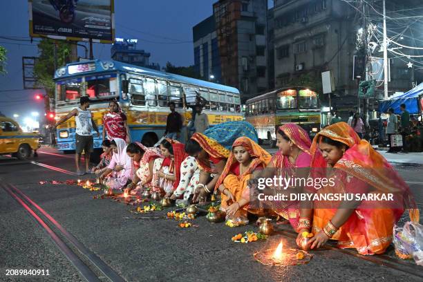 Hindu married women perform a special a prayer in the junction of a busy road as a part of religious rituals for the upcoming Hindu festival of Holi...