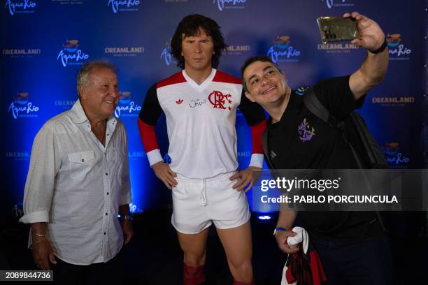 Brazilian former footballer Zico poses for a selfie with a fan next to his wax statue after its inauguration at the AquaRio's Wax Museum in Rio de...
