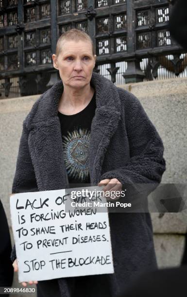 Protester with her newly shaved head holds a sign saying 'Lack of Water is Forcing Women to Shave Their Heads to Prevent Diseases, Stop the Blockade'...