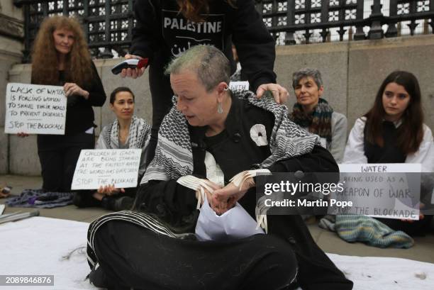 Protester stuffs an envelope with her hair outside the Houses of Parliament on March 19, 2024 in London, England. Due to the ongoing war between...