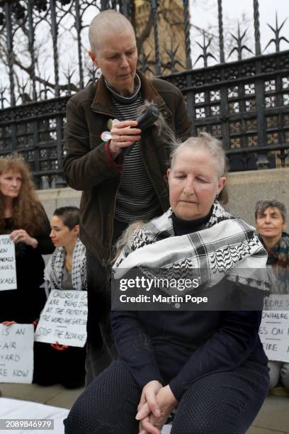 Protester shaves off the hair of a colleague outside the Houses of Parliament on March 19, 2024 in London, England. Due to the ongoing war between...