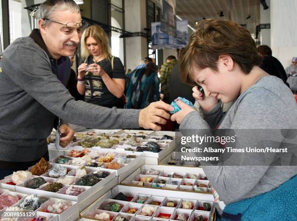 Vendor Mike Szalaj, left, of Youngstown, Ohio, shows Lorelei Gnerre of Lakeville, Conn., how to use a loupe to examine a Shattuckite with Chrysocolla...
