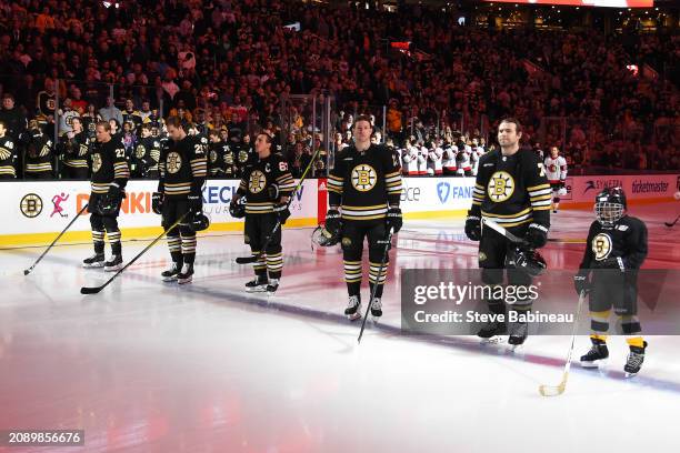 Hampus lindholm, Brandon Carlo, Brad Marchand, Charlie Coyle, and Jake DeBrusk of the Boston Bruins stand on the ice for the National Anthem with...