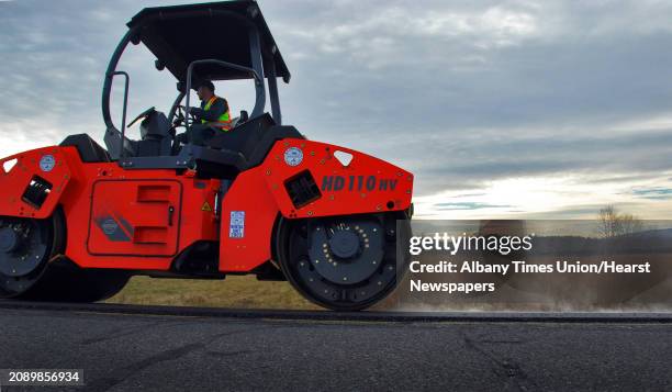 Times Union staff photo by John Carl D'Annibale A member of the Gorman Group paving crew rolls out new asphalt made with recycled tires on county...