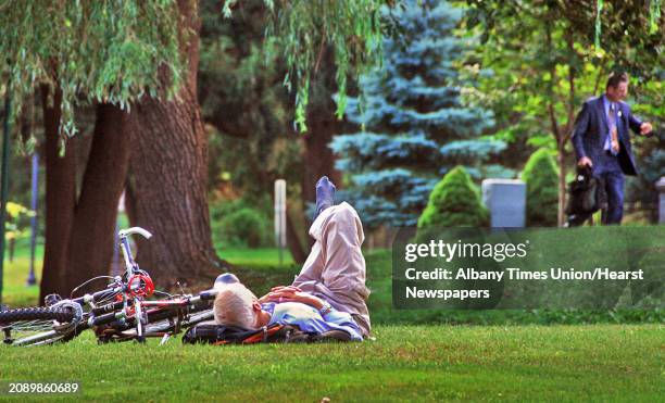 Times Union staff photo by John Carl D'Annibale: An unidentified man in a business suit looks at his watch as Donald McCoy of Saratoga Springs rests...