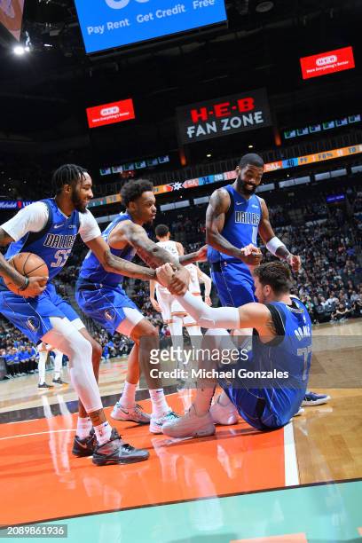 Luka Doncic of the Dallas Mavericks is helped up by Kyrie Irving, PJ Washington and Derrick Jones Jr. #55 during the game against the San Antonio...