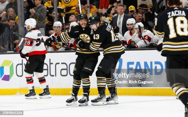 David Pastrnak of the Boston Bruins celebrates his hat trick against the Ottawa Senators with teammate Danton Heinen during the third period at the...