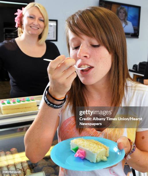 Sweet Temptations owner Nina Crisafulli, left, looks on as Jen Cahill of Colonie samples a free slice of cake featuring the shop's homemade trans...