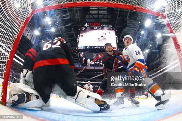 Bo Horvat of the New York Islanders is defended by Brett Pesce of the Carolina Hurricanes as Pyotr Kochetkov tends net during the second period at...