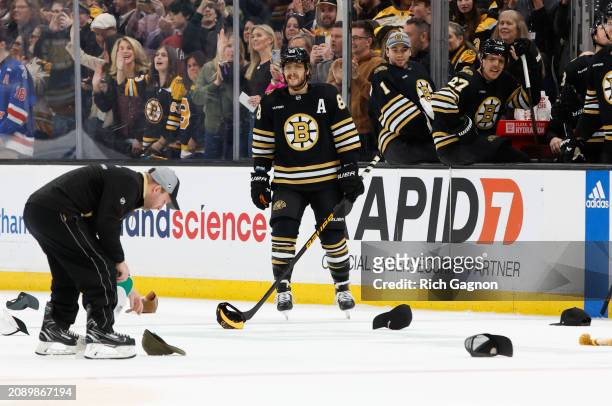 David Pastrnak of the Boston Bruins skates through hats that were thrown on the ice surface after his hat trick against the Ottawa Senators during...