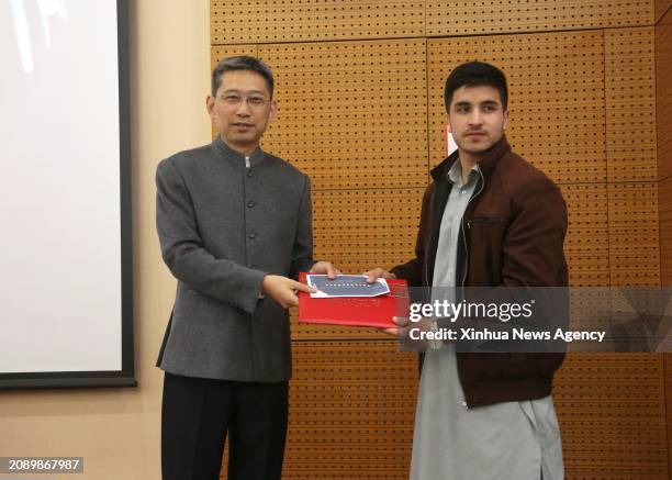 Chinese Ambassador to Afghanistan Zhao Xing L presents awards to an Afghan student who won the "Chinese Ambassador Scholarship" at Kabul University...