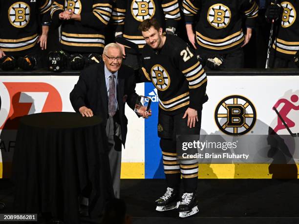 James van Riemsdyk of the Boston Bruins poses for a picture with Johnny Bucyk during a ceremony for playing in 1,000 NHL games before a game against...