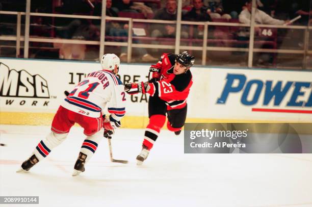 Center Scott Gomez of the New Jersey Devils shoots the puck in the game between the New Jersey Devils vs the New York Rangers at Madison Square...