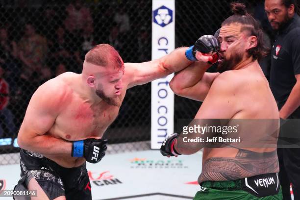 Marcin Tybura of Poland punches Tai Tuivasa of Australia in their heavyweight fight during the UFC Fight Night event at UFC APEX on March 16, 2024 in...