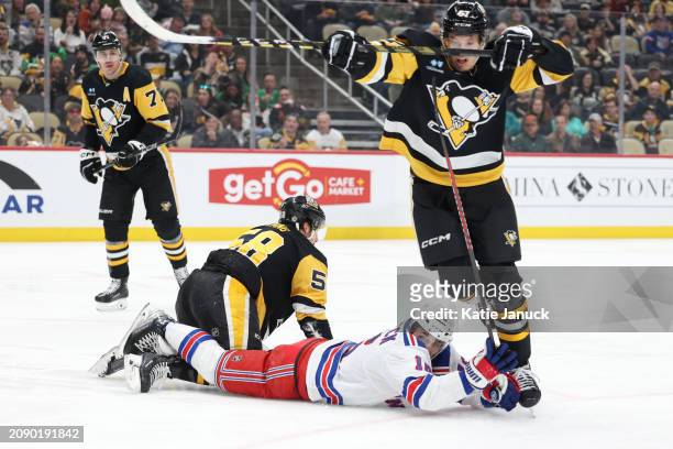 Vincent Trocheck of the New York Rangers trips Rickard Rakell of the Pittsburgh Penguins at PPG PAINTS Arena on March 16, 2024 in Pittsburgh,...
