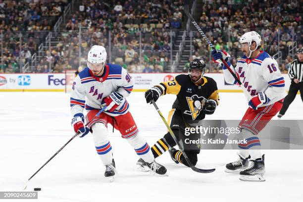 Jack Roslovic of the New York Rangers controls puck against Pierre-Olivier Joseph of the Pittsburgh Penguins at PPG PAINTS Arena on March 16, 2024 in...