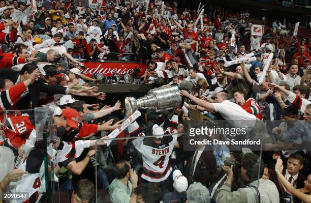 Scott Stevens of the New Jersey Devils carries the Stanley Cup holds up the Stanley Cup after beating the Mighty Ducks of Anaheim in game seven of...