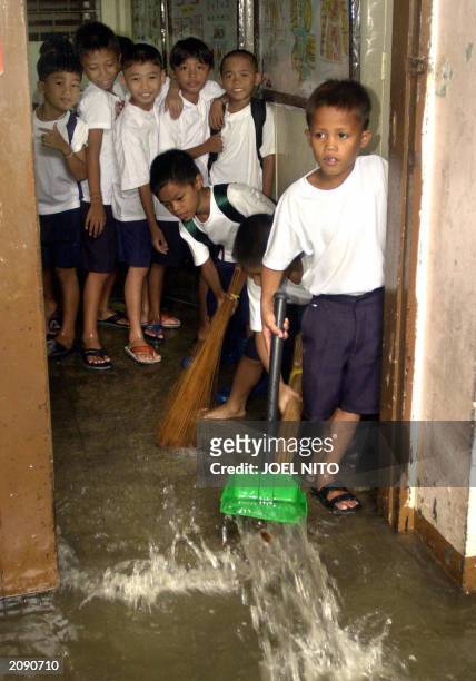 School chidlren in suburban Navotas town in the Philippines try to fight back floodwaters from creeping into their classroom, 17 June 2003. Heavy...
