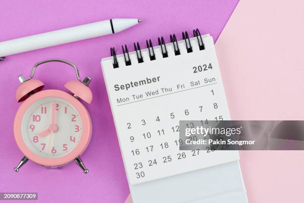 desk calendar 2024: september calendar is used to plan daily work and life with white pen and alarm clock against a two-tone background. - septiembre fotografías e imágenes de stock