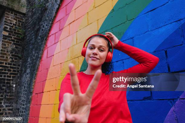 vibrant peace sign and smile at rainbow wall - vibrant stock pictures, royalty-free photos & images