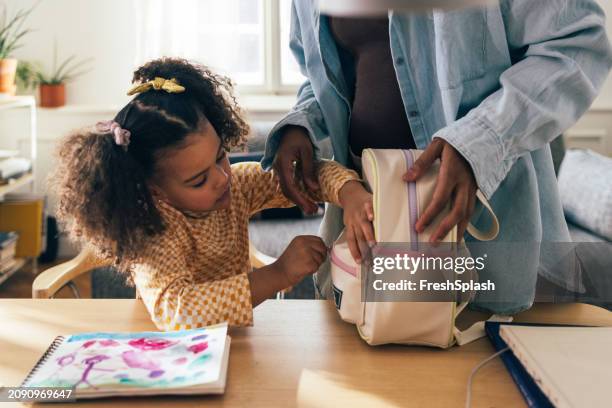 madre ayudando a su hija a prepararse para la escuela en casa - mochila-bolsa fotografías e imágenes de stock