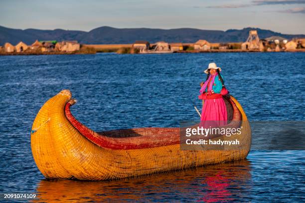 peruvian woman sailing between uros floating islands, lake tititcaca - uroseilanden stockfoto's en -beelden