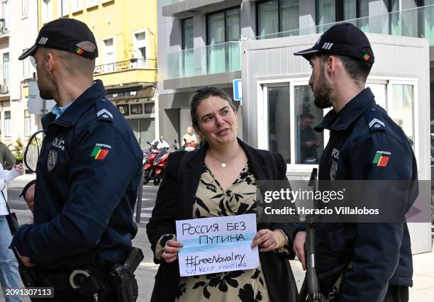 Woman stands with a "We Keep Fighting" sign between two Portuguese policemen as Russian residents in Portugal gather to demonstrate against Russian...