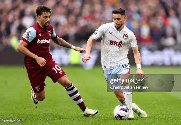 Alex Moreno of Aston Villa runs with the ball whilst under pressure from Lucas Paqueta of West Ham United during the Premier League match between...