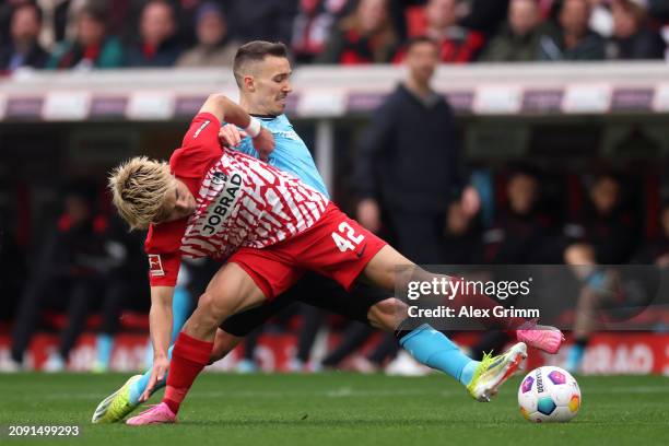 Ritsu Doan of SC Freiburg is challenged by Alex Grimaldo of Bayer Leverkusen during the Bundesliga match between Sport-Club Freiburg and Bayer 04...