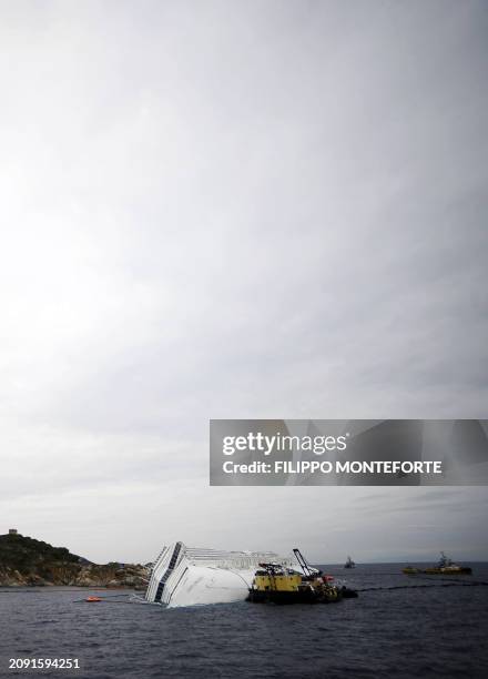 Technicians work near the cruise liner Costa Concordia liying aground in front of the Isola del Giglio on January 27, 2012 after hitting underwater...