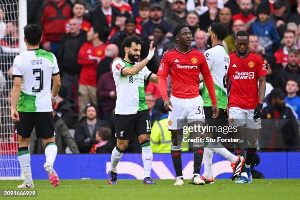 Kobbie Mainoo and Aaron Wan-Bissaka of Manchester United look dejected as Mohamed Salah of Liverpool celebrates scoring his team's second goal with...