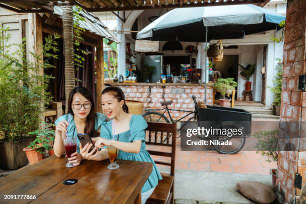 Two joyful women sitting together at an outdoor street cafe in Hanoi, Vietnam