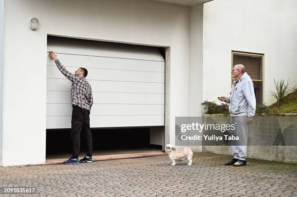 family closing rolling garage door. - multi generational family with pet stock pictures, royalty-free photos & images