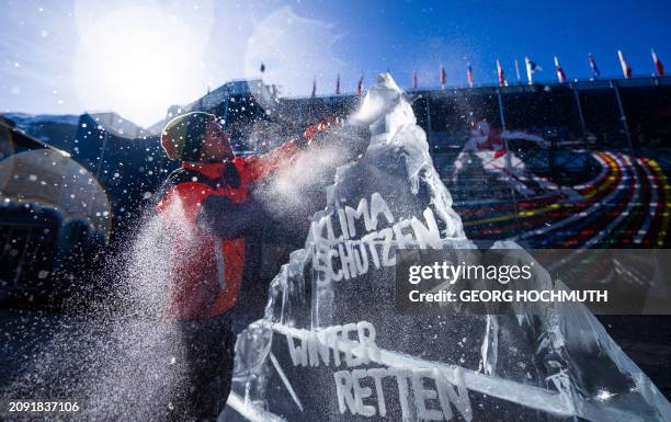 Man carves an ice sculpture shaped like a mountain with the inscription "Protect the climate - Save winter" during a Greenpeace action to demonstrate...