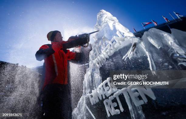 Man carves an ice sculpture shaped like a mountain with the inscription "Protect the climate - Save winter" during a Greenpeace action to demonstrate...