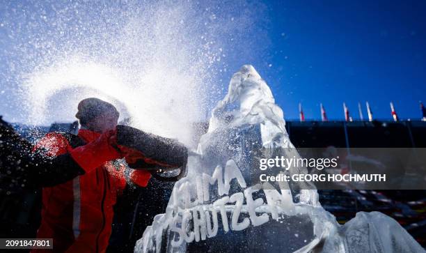 Man carves an ice sculpture shaped like a mountain with the inscription "Protect the climate" during a Greenpeace action to demonstrate for the...